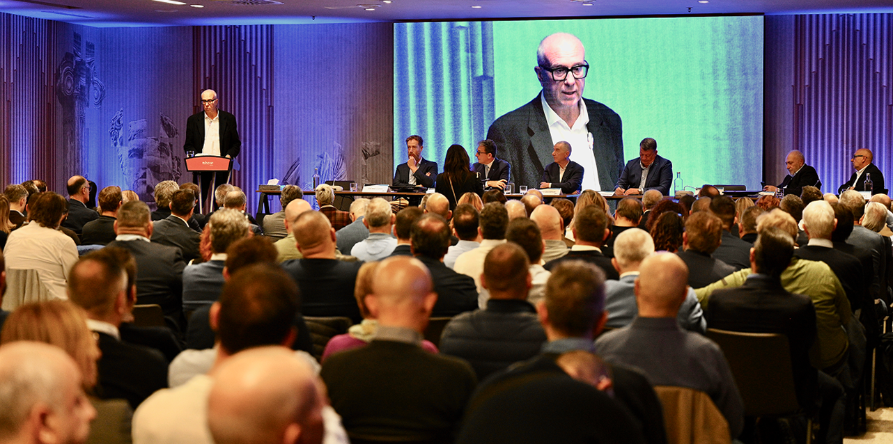 Copertina della rivista 'News dal Sindacato' della FenealUIL su un tavolo in legno, accanto a un casco da cantiere giallo, strumenti da lavoro e rotoli di progetti. Testo: 'Leggi il nuovo numero della rivista della FenealUIL'.