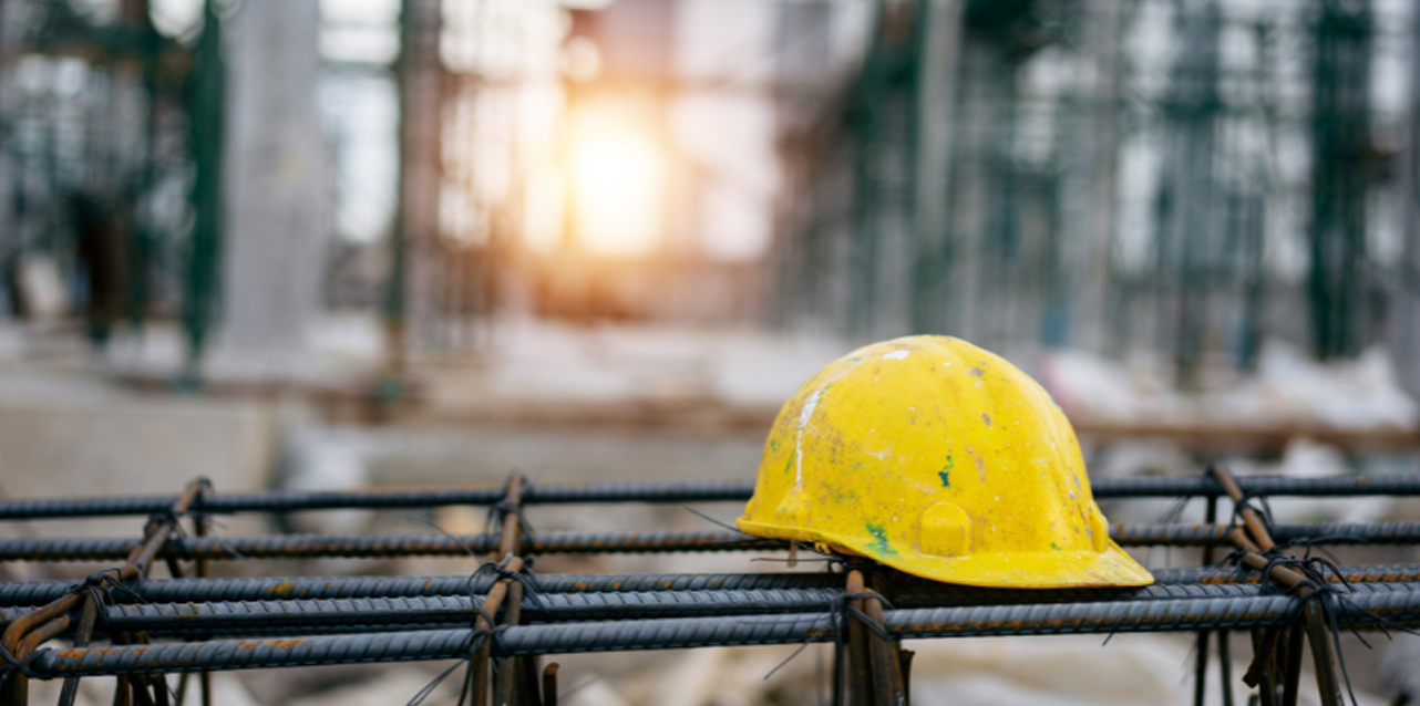 Immagine-editoriale 1 Copertina della rivista 'News dal Sindacato' della FenealUIL su un tavolo in legno, accanto a un casco da cantiere giallo, strumenti da lavoro e rotoli di progetti. Testo: 'Leggi il nuovo numero della rivista della FenealUIL'.